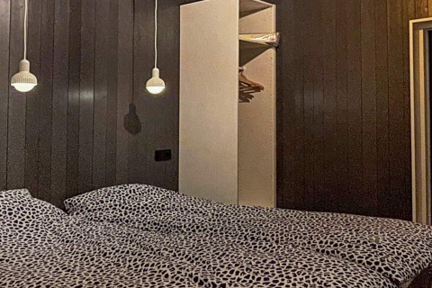 Dormitorio en Spacious Lakeside Villa en Suecia con paredes oscuras, cama y armario abierto moderno.