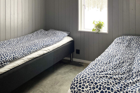 Deux lits simples avec draps bleus dans une chambre moderne à Spacious Lakeside Villa, fenêtre avec vue.