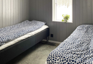 Deux lits simples avec draps bleus dans une chambre moderne à Spacious Lakeside Villa, fenêtre avec vue.