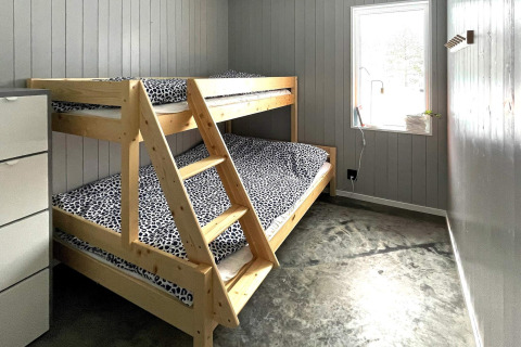 Zimmer in einer Lodge mit Etagenbett, Leopardenmuster-Bettwäsche, grauen Wänden und Fenster, Schweden.