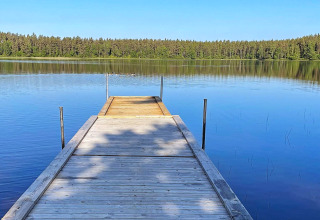 Molo di legno su lago tranquillo con foresta sullo sfondo, foto scattata in Svezia presso una villa.