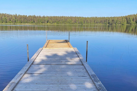 Ponton en bois sur un lac paisible bordé de forêt, photo prise en Suède depuis une maison de vacances.