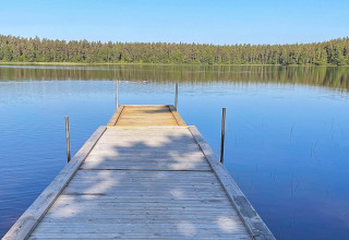 Molo di legno su lago tranquillo con foresta sullo sfondo, foto scattata in Svezia presso una villa.