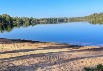 Rustig uitzicht op het meer met zandstrand bij Spacious Lakeside Villa with in Zweden op een zonnige dag.