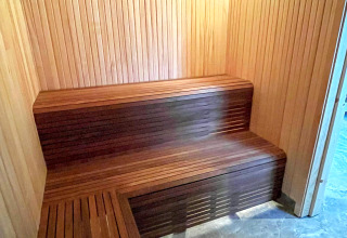Vista interna di una sauna moderna in legno con panche in una spaziosa villa sul lago in Svezia.