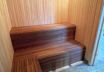 Binnenaanzicht van een moderne houten sauna met banken in een ruime villa aan het meer in Zweden.