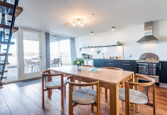 Modernes Hausboot mit offener Küche, Essbereich und Terrasse im 6-Personen-Ferienhaus in Hemmet, Dänemark.