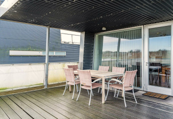 Terrasse couverte sur une péniche avec table à manger et six chaises dans une maison de vacances à Hemmet, Danemark.
