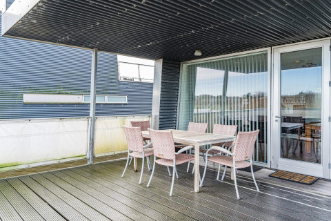 Overdækket terrasse på husbåd med spisebord og seks stole ved 6 personers feriehus i Hemmet, Danmark.