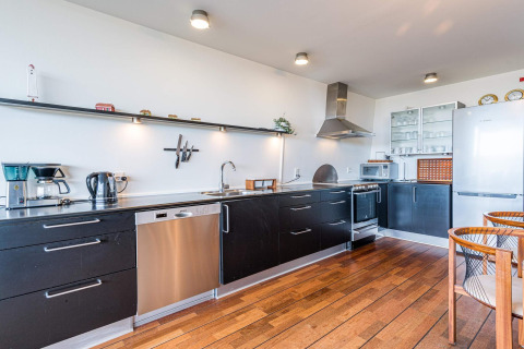 Cucina moderna su houseboat con mobili neri, pavimento in legno e elettrodomestici acciaio a Hemmet, Danimarca.