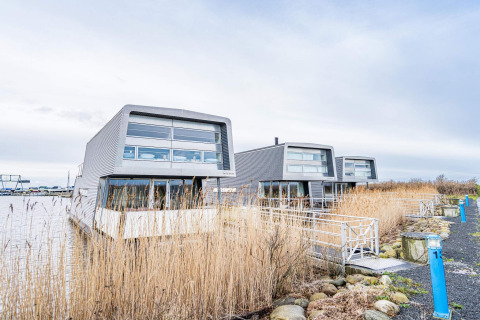 Casa flotante moderna 'Casa vacacional para 6 personas en Hemmet', Dinamarca, junto al agua y vegetación.