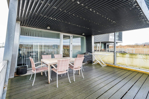 Groot overdekt terras met eettafel en stoelen op een woonboot in Hemmet, Denemarken aan het water.
