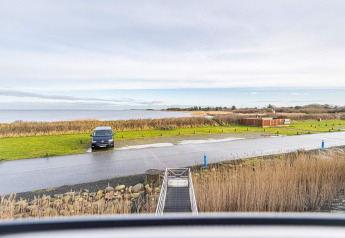 Vue d’une péniche sur le parking, la pelouse et la mer à Hemmet, Danemark, maison de vacances 6 personnes.