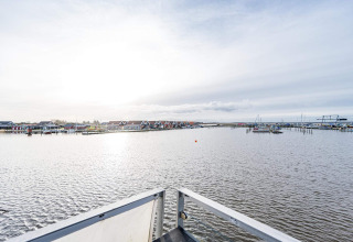 Vista desde una casa flotante en Hemmet, Dinamarca, con agua, botes y coloridas cabañas al fondo.