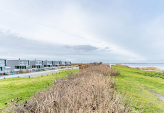 Moderne woonboten aan het water in Hemmet, Denemarken, met uitzicht op grasvelden en zee.