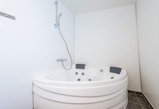 Vasca idromassaggio angolare e doccia in un luminoso bagno di houseboat a Hemmet, Danimarca.