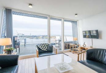 Living room on a houseboat in Hemmet, Denmark, with modern décor, large windows, and marina and terrace views.