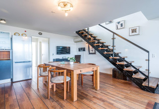 Area soggiorno e cucina moderna su una casa galleggiante con tavolo da pranzo, sedie e scala a Hemmet, Danimarca.