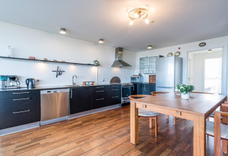 Cucina moderna e zona pranzo su una casa galleggiante a Hemmet, Danimarca, con pavimenti in legno e elettrodomestici.