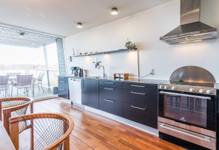 Cocina moderna en casa flotante en Hemmet, Dinamarca, con gabinetes oscuros, horno y vista a la terraza.