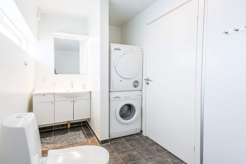 Baño moderno con lavadora y secadora apiladas en casa flotante para 6 personas en Hemmet, Dinamarca.