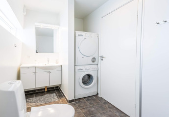 Modern bathroom with stacked washer and dryer in a 6 person holiday home in Hemmet, Denmark.