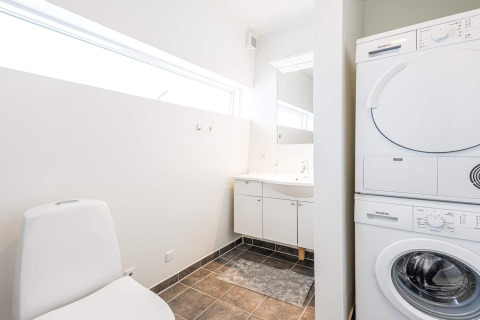 Modern lichte badkamer met was-droogcombinatie op een woonboot in Hemmet, Denemarken.