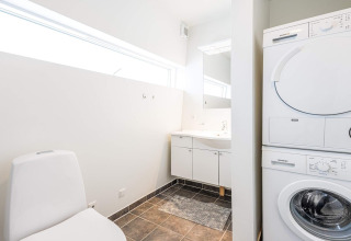 Modernes Badezimmer mit Waschmaschine und Trockner in einem Hausboot-Ferienhaus in Hemmet, Dänemark.