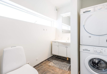 Salle de bain moderne et lumineuse avec lave-linge et sèche-linge sur une péniche à Hemmet, Danemark.