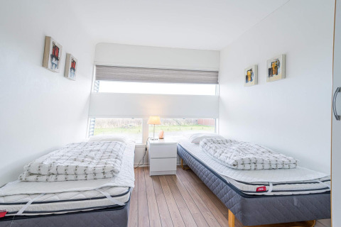 Lichte, moderne slaapkamer op woonboot in Hemmet, Denemarken, met twee eenpersoonsbedden en groot raam.