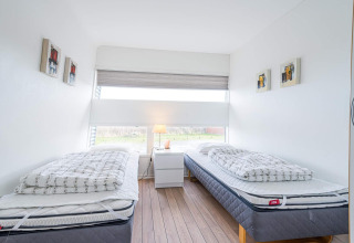Luminoso dormitorio moderno su una casa galleggiante a Hemmet, Danimarca, con due letti singoli e finestra.