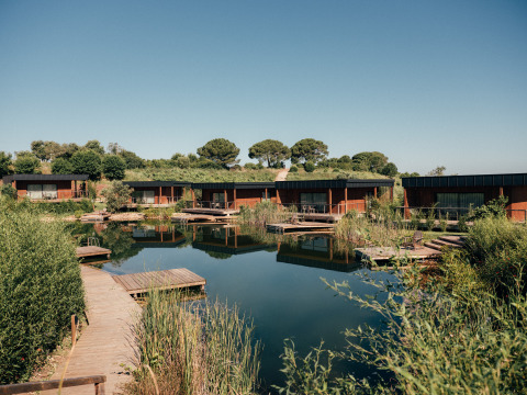 Vakantiepark Wecamp Reserva Alecrim in Alentejo, Portugal, met moderne lodges rond een vijver in het groen.