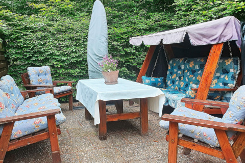 Area soggiorno esterna di una casa vacanze a TJÖRNARP, Svezia, con dondolo da giardino e cuscini blu.