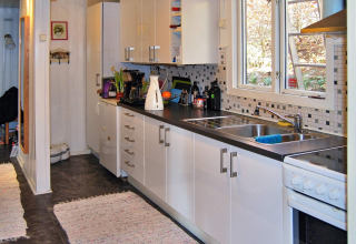 Moderne vakantiehuiskeuken in Tjörnarp, Zweden, met witte kasten, zwart aanrecht en grote ramen.