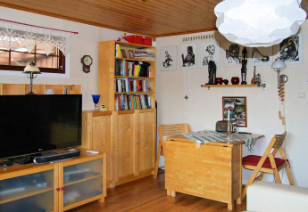 Gezellige woonkamer in een houten hut met boekenkast, tv, eettafel en kunst in Tjörnarp, Zweden.