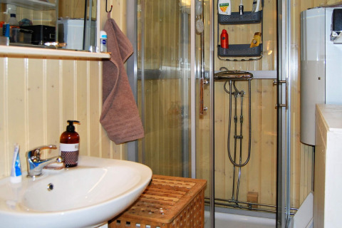 Badkamer met houten wanden, douche en wastafel in een vakantiehuis in Tjörnarp, Zweden.