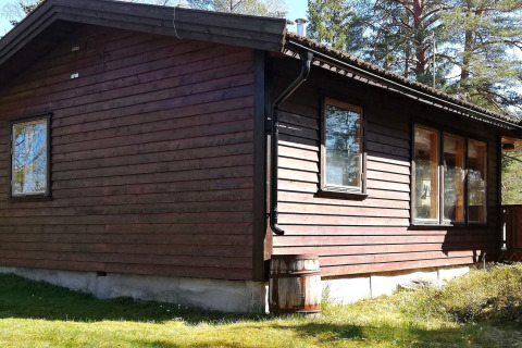 Façade ensoleillée du '4 person holiday home in NORRTÄLJE', un gîte en bois entouré de verdure et d’arbres en Suède.