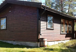 Vista exterior soleada de la cabaña de madera '4 person holiday home in NORRTÄLJE', rodeada de árboles en Suecia.