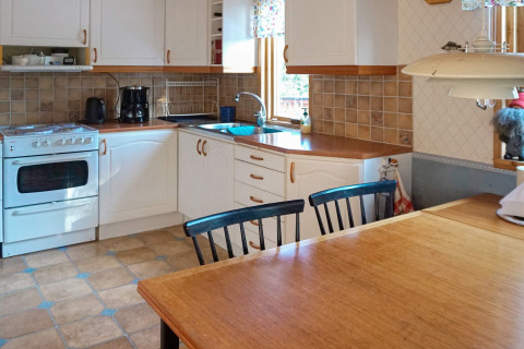 Cocina luminosa en una casa de vacaciones en Norrtälje, Suecia, con mesa de madera, armarios blancos y azulejos.