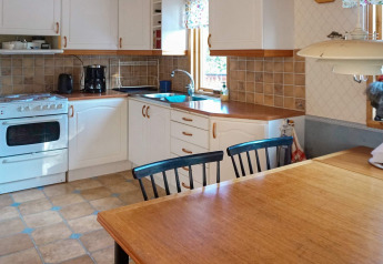 Lichte keuken in een vakantiehuis in Norrtälje, Zweden, met houten tafel, witte kasten en betegeling.