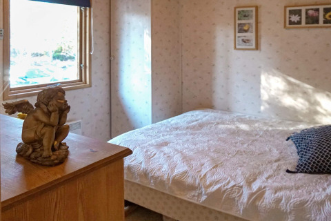 Gezellige slaapkamer in vakantiewoning te Norrtälje, Zweden, met engelbeeldje en bloemen aan de muur.