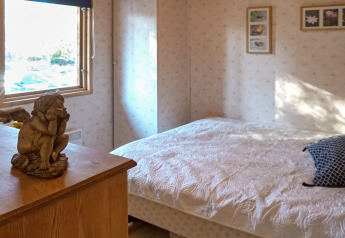 Slaapkamer in vakantiehuis met engelbeel, raam en bloemenkunst aan de muur in Norrtälje, Zweden.
