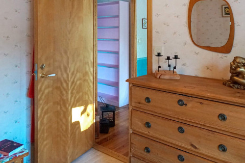 Vista interior de un dormitorio acogedor con cómoda, espejo y pasillo en una casa de vacaciones en Suecia.