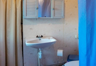 Badezimmer mit Waschbecken, Spiegelschrank, Toilettenpapierhalter und Duschvorhang in Norrtälje, Schweden.