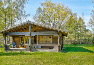 Houten lodge voor 6 personen in Eskebjerg, Denemarken, met groot grasveld en omliggende bomen.