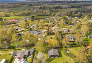 Vista aerea di lodge, alberi e campi in un paesaggio verde a Eskebjerg, Danimarca.