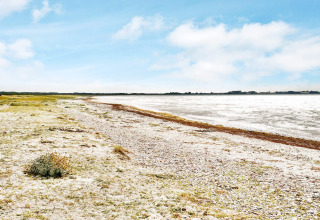 Paysage côtier à Eskebjerg, Danemark, plage de galets et mer ouverte sous un ciel bleu clair.