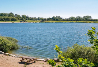 Uitzicht op een rustig meer met picknicktafel en groen bij het 6-persoons huis in Eskebjerg, Denemarken.