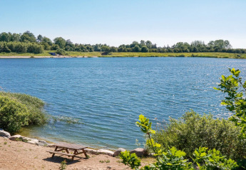 Zicht op een rustige vijver met picknickbank en groen bij de 6-persoonshuis in Eskebjerg, Denemarken.