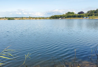 Uitzicht op een rustige meer bij het 6-persoons huisje in Eskebjerg, Denemarken, met hengels vooraan.